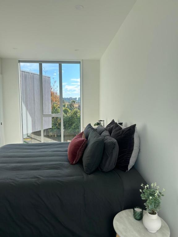 una camera da letto con un letto nero e una grande finestra di Tranquility in Travis a Christchurch