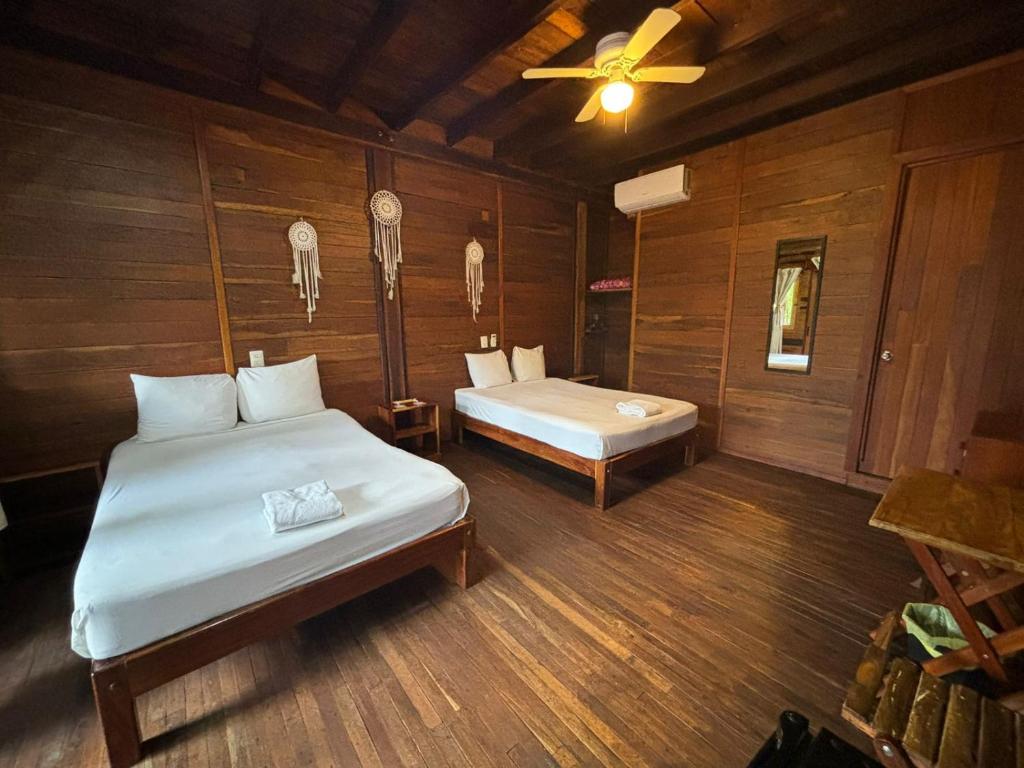 a bedroom with two beds and a ceiling fan at Lura Bacalar in Bacalar