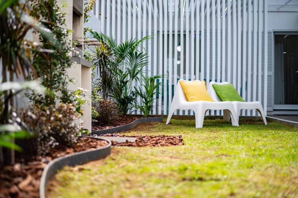 Duas cadeiras brancas com almofadas coloridas num quintal em Casa Cecilia Meireles em Ponta Delgada