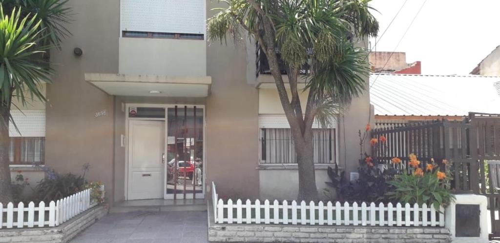 une maison avec une clôture blanche et un palmier dans l'établissement Departamento Cardiel, à Mar del Plata