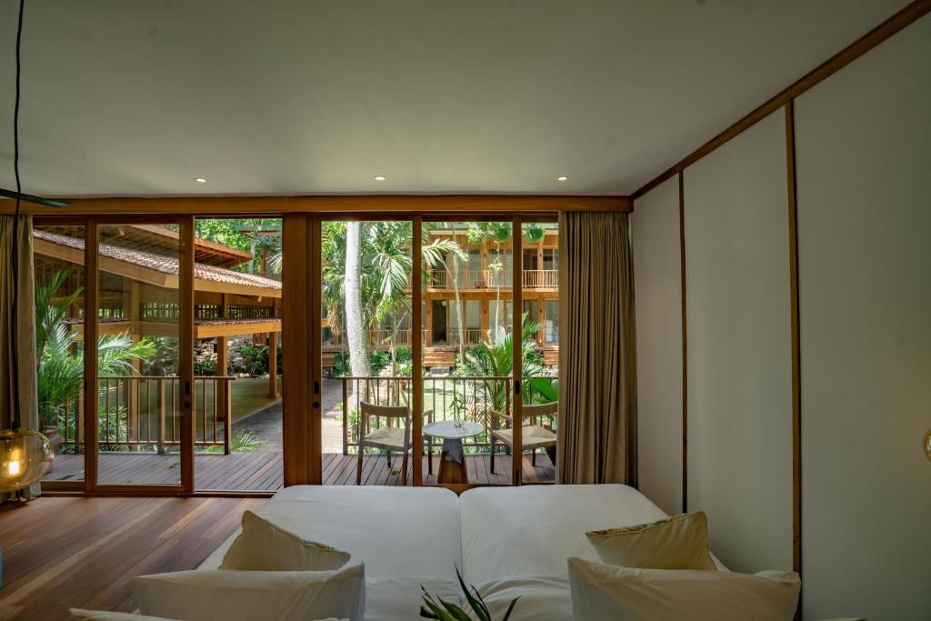 a bedroom with a white bed and a balcony at Grün Resort Uluwatu in Uluwatu