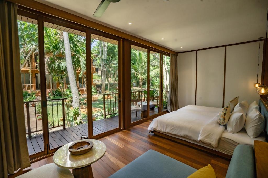 a bedroom with a bed and a large window at Grün Resort Uluwatu in Uluwatu