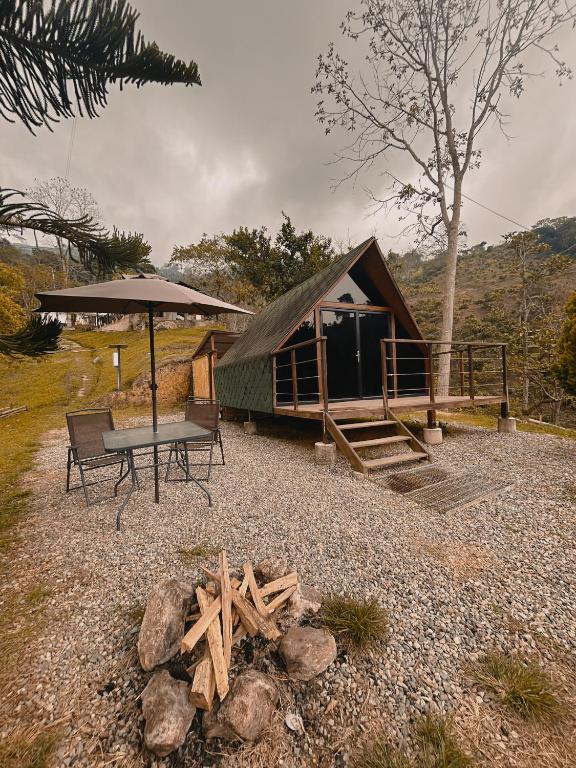 a cabin with a picnic table and an umbrella at Glampling Dos Quebradas in Floridablanca
