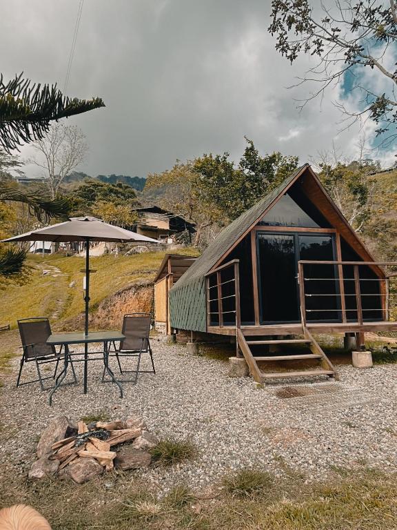 a cabin with a table and chairs and an umbrella at Glampling Dos Quebradas in Floridablanca