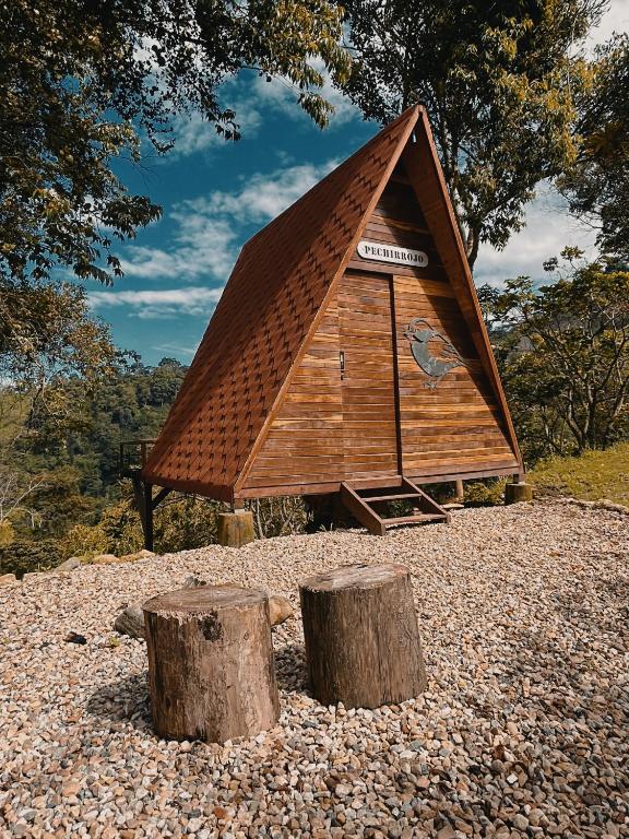 a small cabin with a triangular roof and two logs at Glampling Dos Quebradas in Floridablanca