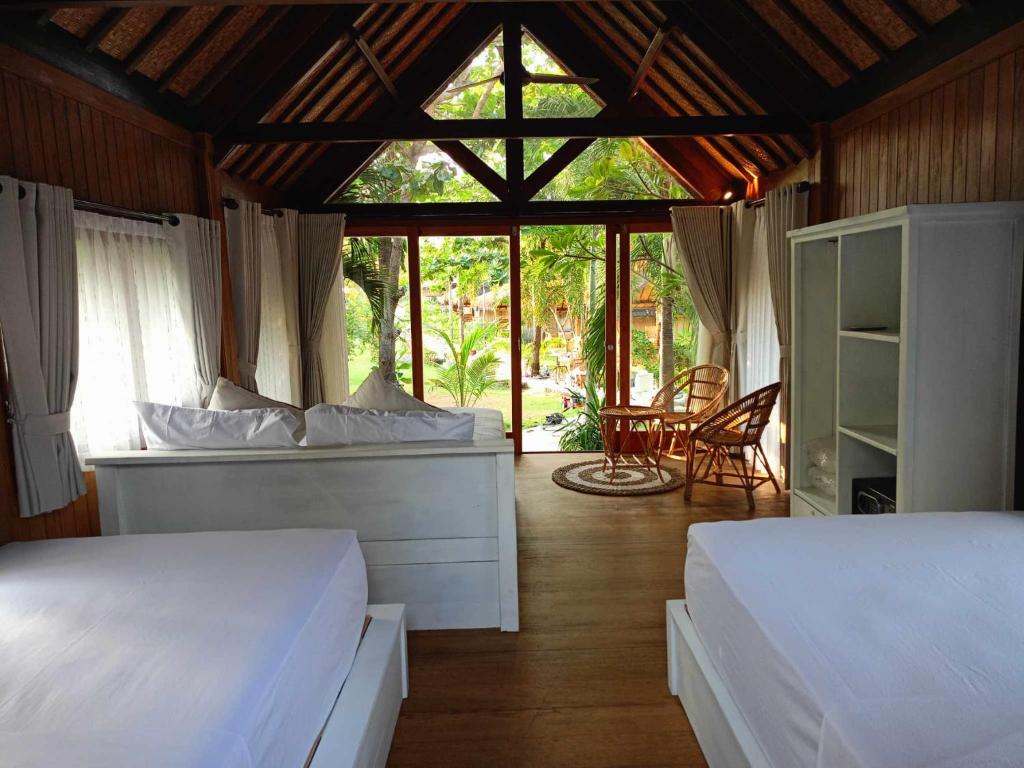 1 dormitorio con 2 camas y ventana en Bintang Tiga Bungalows Gili Air en Gili Air