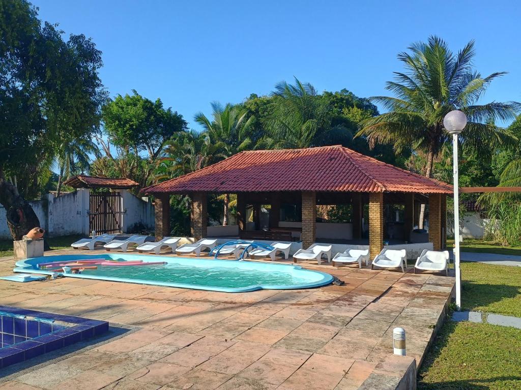 a swimming pool with lounge chairs and a gazebo at Pousada Villa do Mar in Itaparica Town