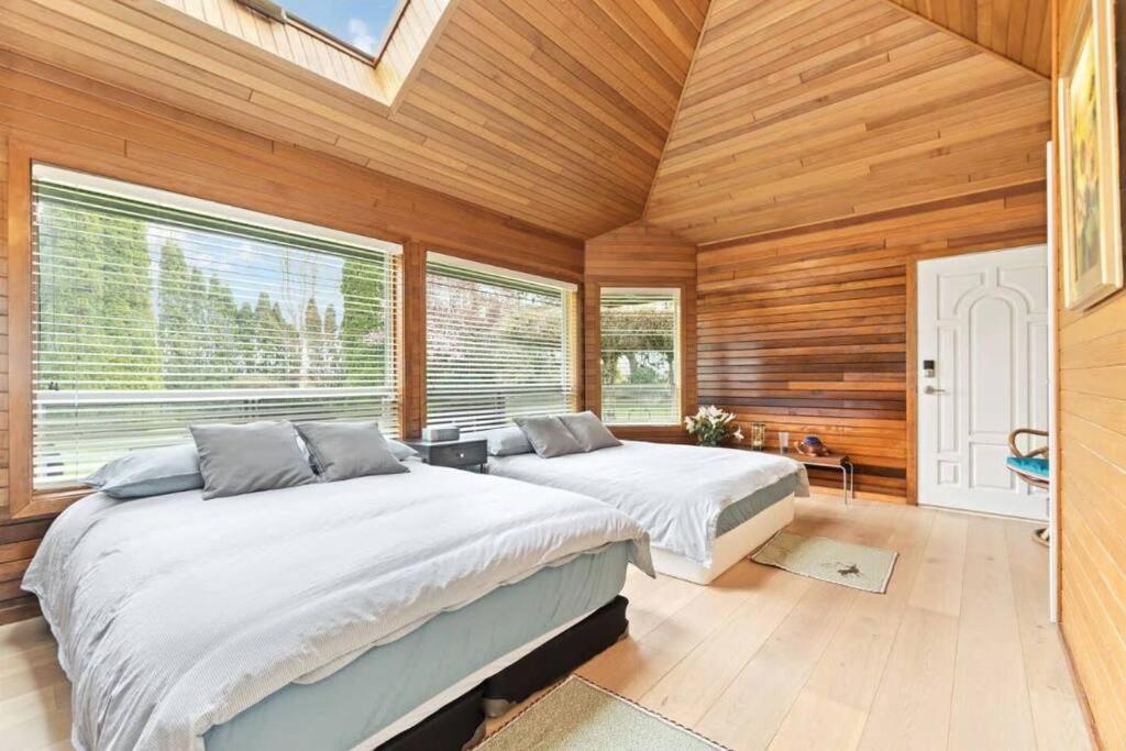 2 camas en una habitación con paredes y ventanas de madera en Cozy Retreat in Richmond en Richmond