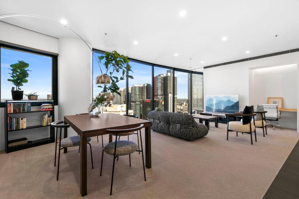 Sydney Sky high Self-Catering في سيدني: غرفة معيشة مع طاولة وكراسي ونوافذ كبيرة