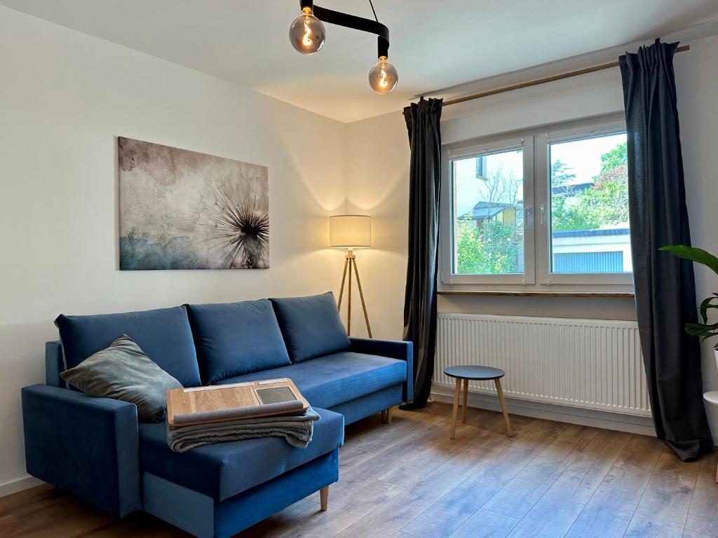 a living room with a blue couch and a window at Ferienwohnung Rheingrafenblick mit Infrarotkabine in Bad Kreuznach