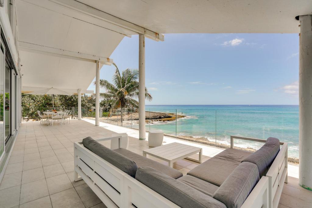 an outdoor patio with a couch and a view of the ocean at Luxe Oceanfront Waianae Home with Lanai - Near Beach in Waianae