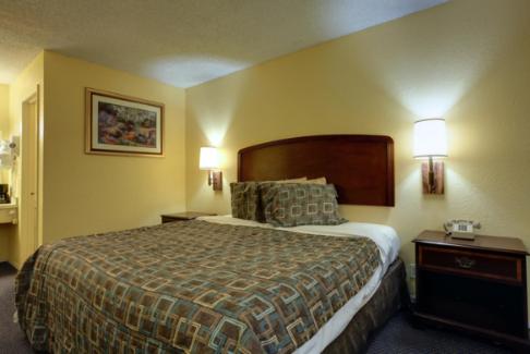Americas Best Value Inn Comanche في Comanche: غرفة فندقية بسرير كبير ومصباحين