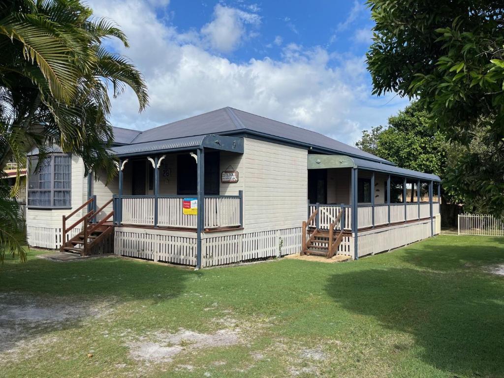 ein weißes Haus mit einem schwarzen Dach und einem Hof in der Unterkunft Cooloola Cottage Rainbow Beach in Rainbow Beach