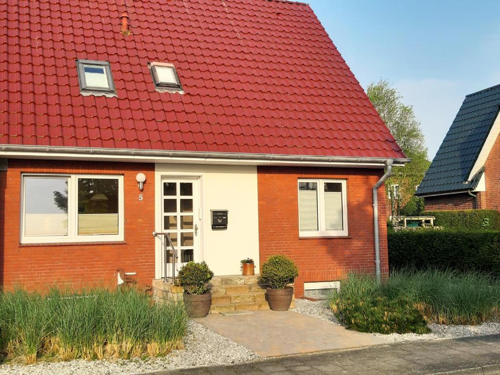 uma casa vermelha e branca com um telhado vermelho em Ferienhaus Mien Huske em Norderney