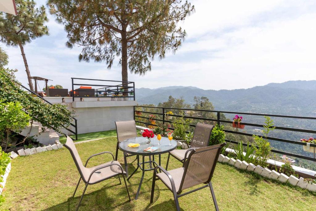 a patio with a table and chairs on the grass at Villa Woodside Meadows by VEO - 3BR with Free BF, Apple Orchard, & Jacuzzi in Kasauli