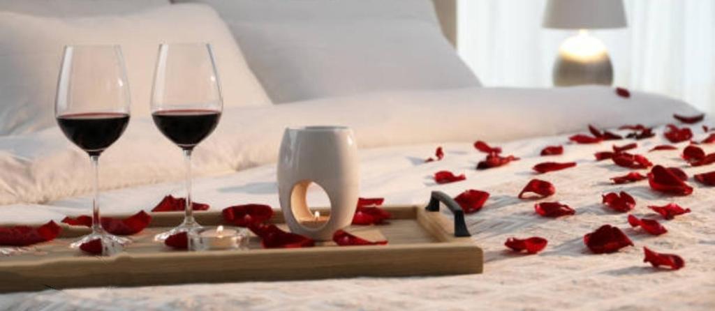 deux verres de vin et des roses rouges sur un lit dans l'établissement Aurora appartamento, intero appartamento di 105 mq, à Terni