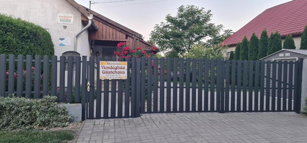 Una cerca negra con un cartel en frente de una casa en Harmónia Vendégház, en Poroszló