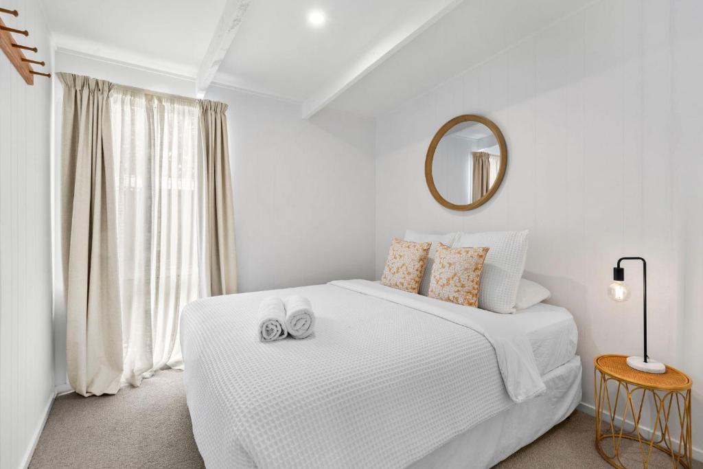 a white bedroom with a bed and a mirror at The Cottage- Pet friendly, Golf, Ocean and River! in Ocean Grove