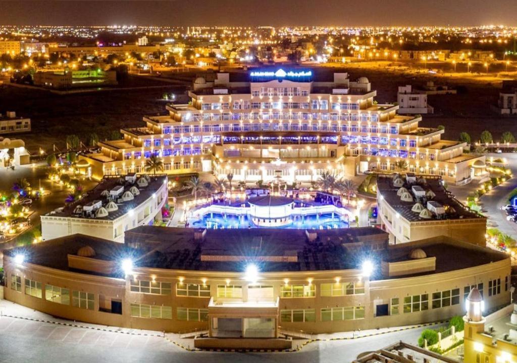 - une vue aérienne sur un grand bâtiment la nuit dans l'établissement Al Salam Grand Hotel & Resort, à Al Buraymī