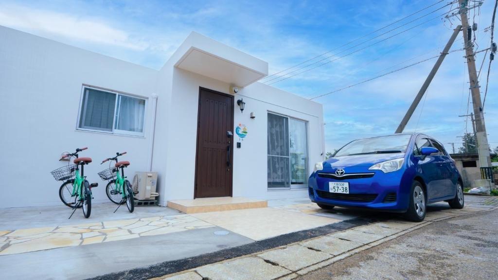 een kleine blauwe auto geparkeerd voor een wit huis bij BLUE SOLARE 1 - Vacation STAY 15668v in Miyako Island