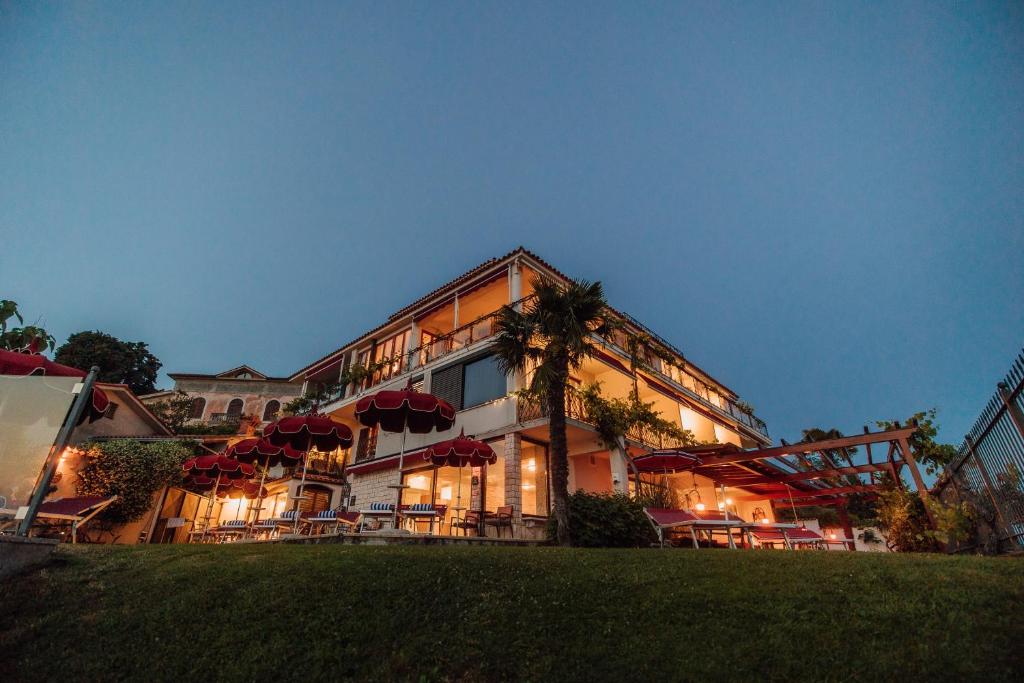 um grande edifício com guarda-chuvas vermelhos em frente em Villa Bellevue Portoroz-Portorose em Portorož