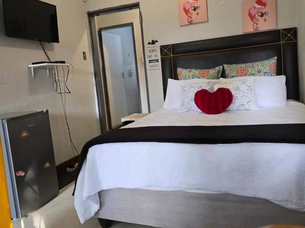 a bedroom with a bed with a heart pillow on it at DREAMLAND GUEST HOUSe in Mahikeng