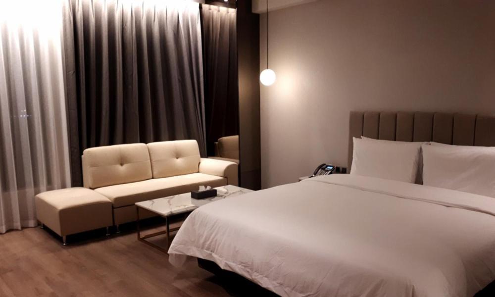 Busan Myeongji Ciel Ocean Hotel في بوسان: غرفة نوم بسرير واريكة وكرسي