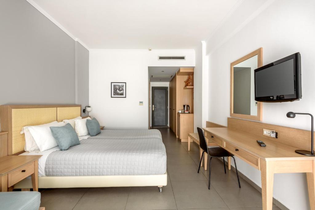 ein Hotelzimmer mit einem Bett, einem Schreibtisch und einem TV in der Unterkunft Libyan Princess in Palaiochóra