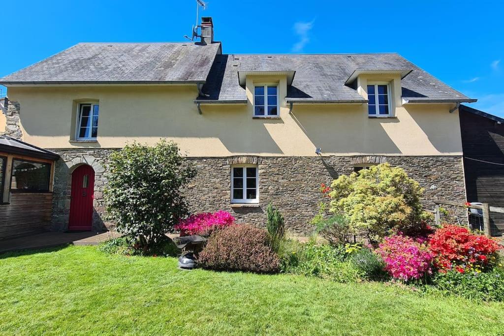 une maison avec une porte rouge et quelques fleurs dans l'établissement Maison au coeur du bocage normand Gourfaleur, à Bourgvallées