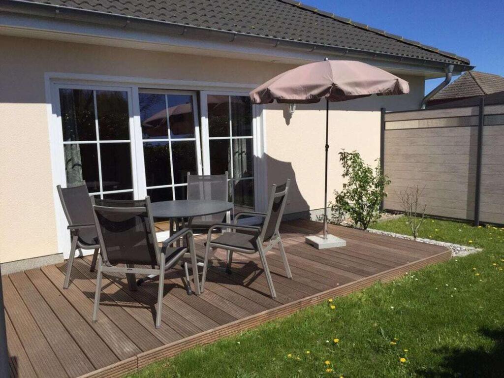 um pátio com uma mesa, cadeiras e um guarda-sol em Boddensurfer 2a Comfortable holiday residence em Pruchten