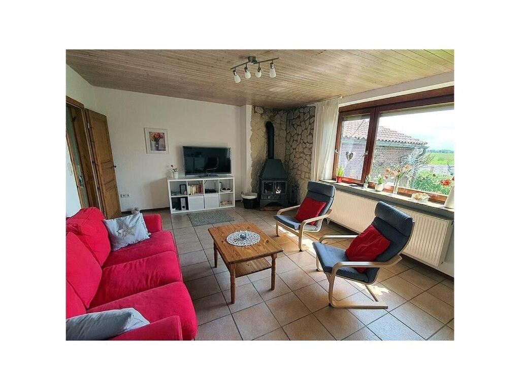 un soggiorno con divano rosso e sedie di Friesenblick Comfortable holiday residence a Buttforde
