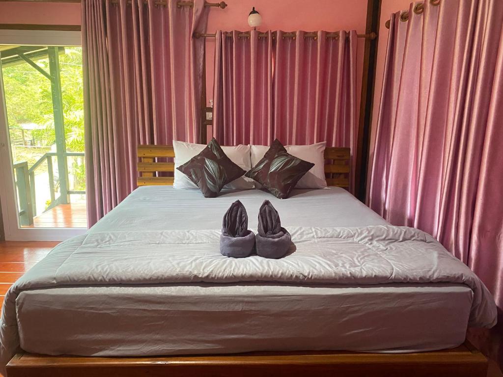 una cama con dos pares de zapatos sentados en ella en Kanitta Homestay, en Ban Bang Chak