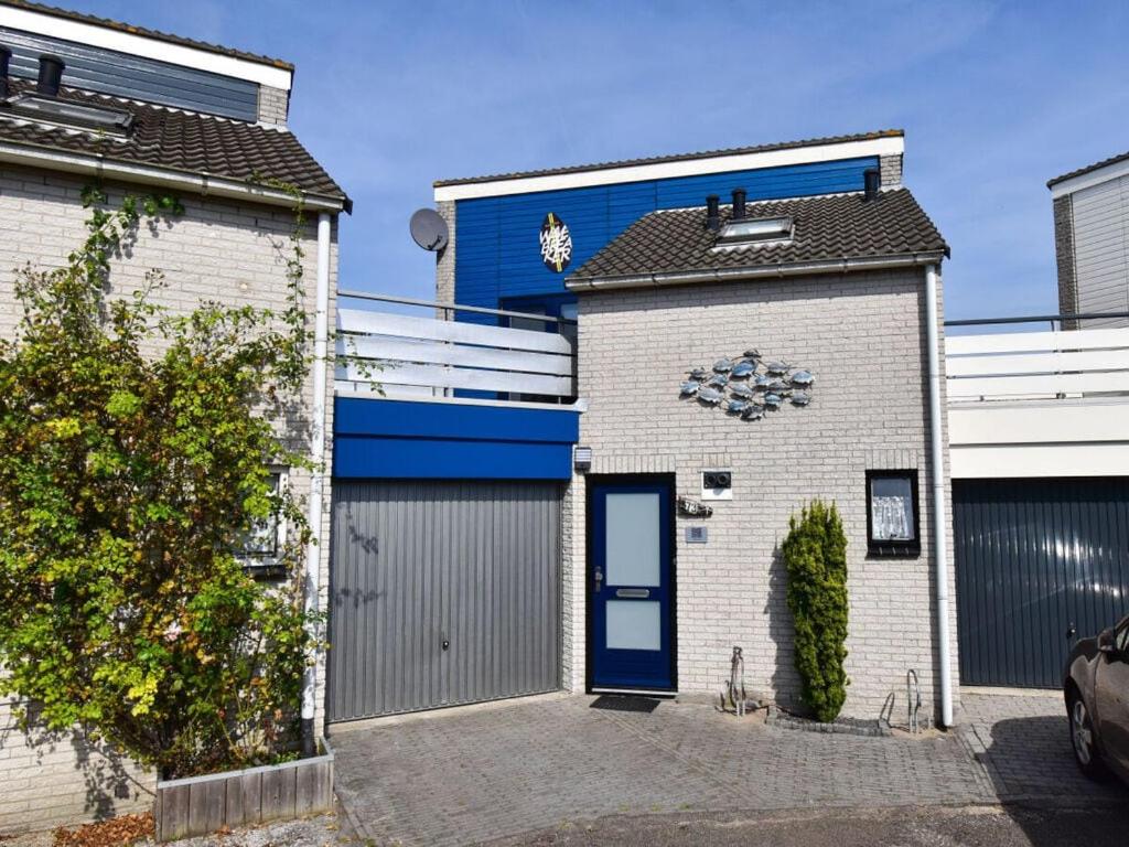 a house with a garage with a blue door at Huijsmansverhuur Type de Luxe plus Haringvliet 173 in Ouddorp