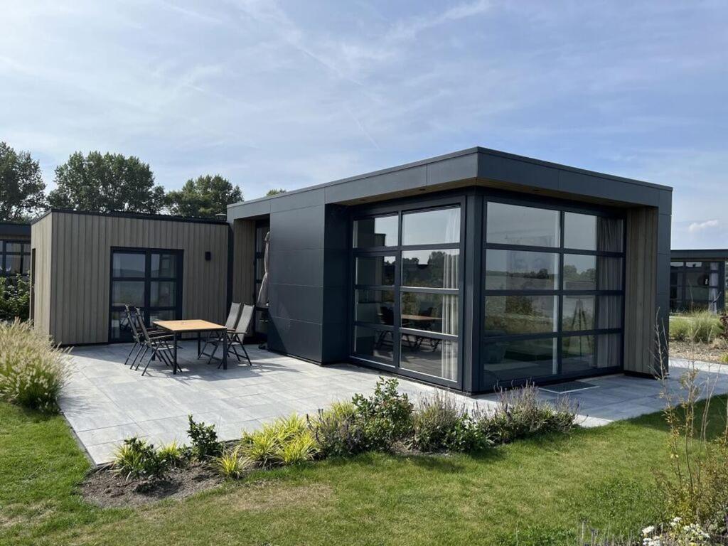 een klein huis met een patio en een tafel bij Chalet IJsselmeerstrand First row in Enkhuizen