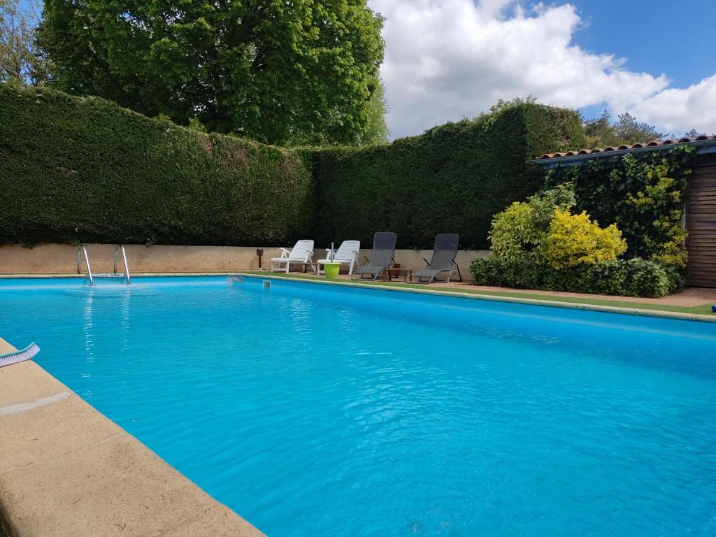 uma grande piscina azul com cadeiras e arbustos em Chez Isa et Dens em Marsac-sur-lʼIsle