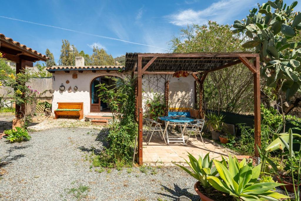 a patio with a table and chairs in a garden at Beach Room Apartment in Quartu SantʼElena