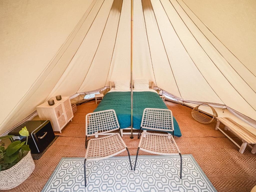 a tent with two chairs and a bed in it at Strandbad Steckborn mit Herberge, Camping & Glamping in Steckborn