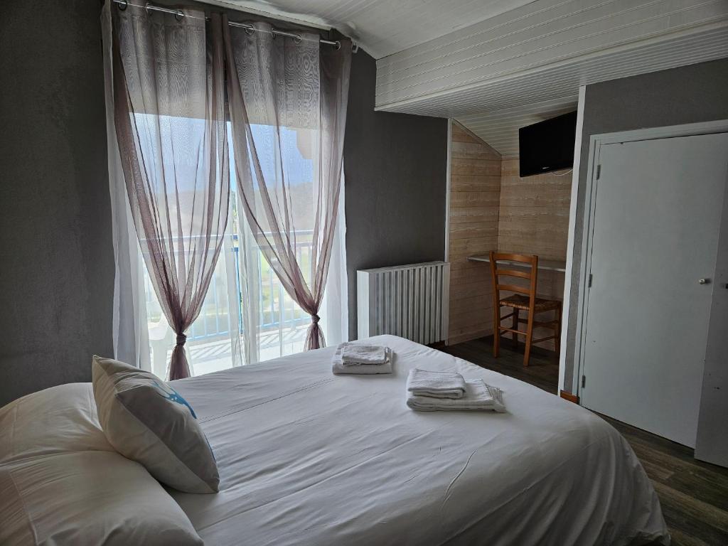 a bedroom with a white bed with a large window at Hôtel L'Oustalet in Font Romeu Odeillo Via