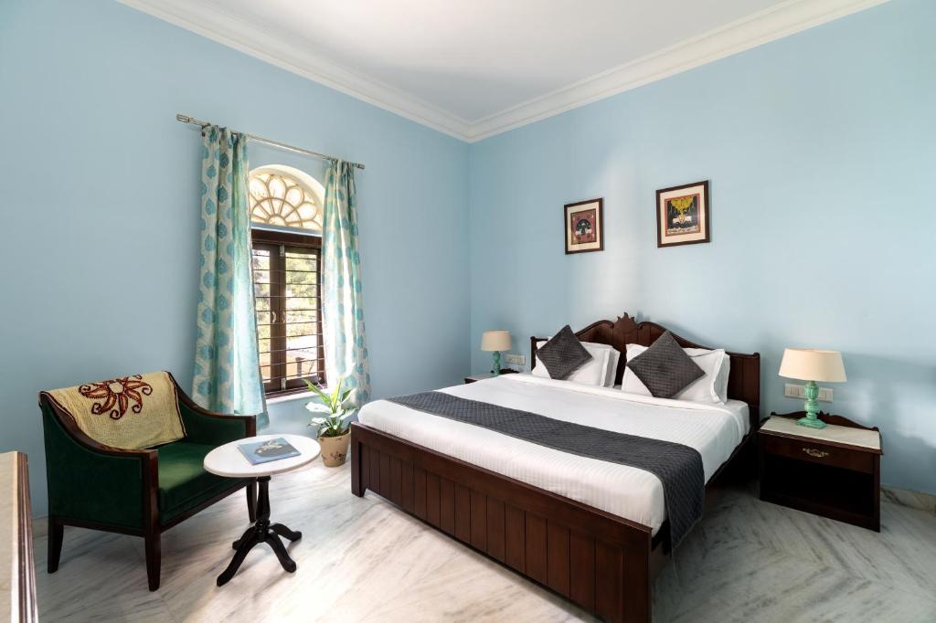 ウダイプールにあるChandra Vilas Heritage stayのベッドと椅子付きのホテルルーム