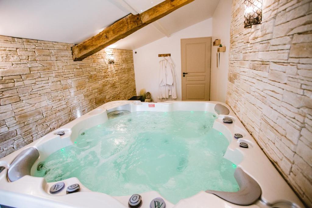 a jacuzzi tub in a bathroom with a stone wall at Gîte Ô Tilleul Enchanté in Lamonzie-Saint-Martin