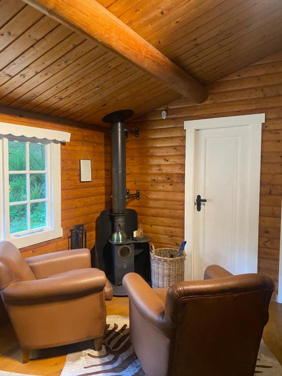 a living room with a stove and leather chairs at 3bears Log Cabin Whatstandwell Matlock Derbyshire in Crich