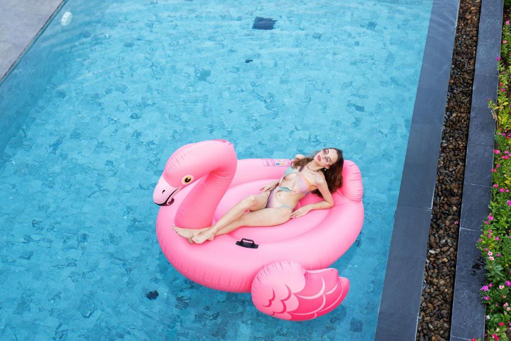 Eine Frau, die auf einem aufblasbaren Flamingo in einem Pool liegt. in der Unterkunft Sivana Villas Hua Hin in Hua Hin