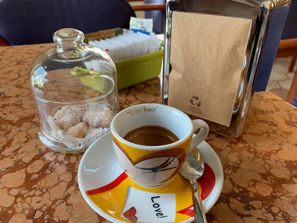 a cup of coffee on a plate on a table at HOTEL al FARO ,SPIAGGIA LA CINTA ,SAN TEODORO in San Teodoro