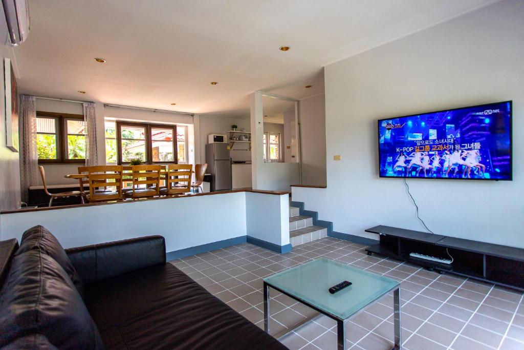 ein Wohnzimmer mit einer Couch und einem Fernseher an der Wand in der Unterkunft F4 Beach house Kitchen BBQ 3 bedrooms Large yard in Rayong