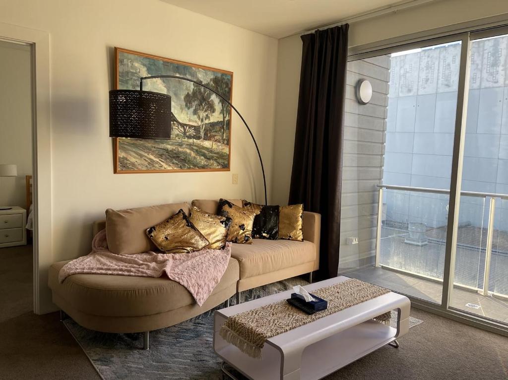 ein Wohnzimmer mit einem Sofa und einem Tisch in der Unterkunft 1BR Adelaide CBD Apt The Best Location in Adelaide