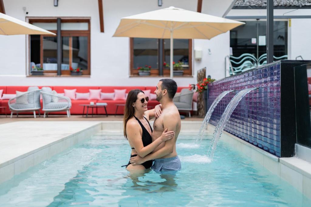 a man and a woman standing in a swimming pool at Neptuno Hotel & SPA 4 Sup in Calella