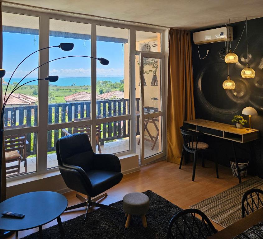 ein Wohnzimmer mit einem Stuhl und einem Balkon in der Unterkunft Трехкомнатный апартамент с видом на море in Aheloy