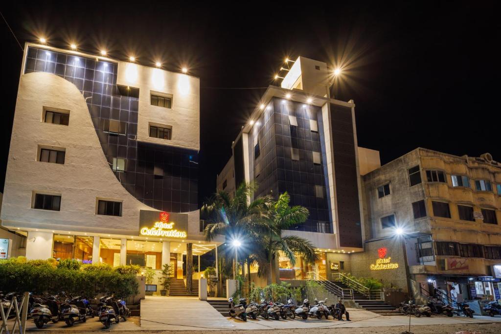 een groep motorfietsen die 's nachts voor gebouwen geparkeerd staan bij Hotel Celebration in Jamnagar