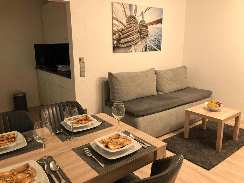 ein Wohnzimmer mit einem Tisch mit Speise- und Weingläsern in der Unterkunft Ambiente Apartment in Bremen