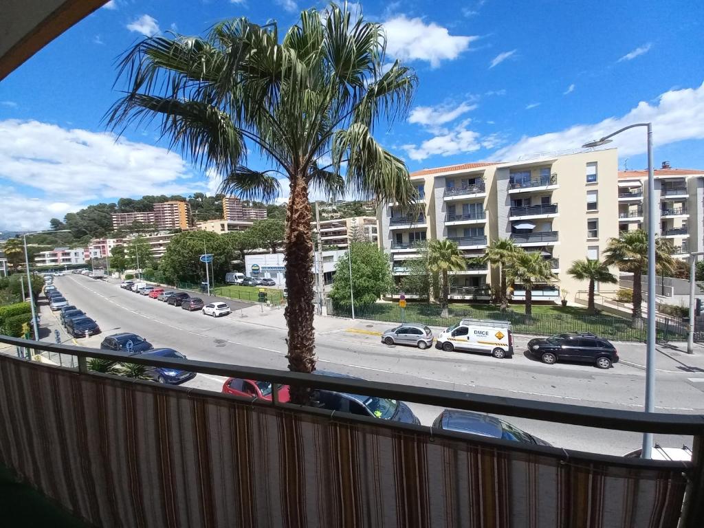 un palmier sur un balcon avec vue sur une rue dans l'établissement Appartement 3 pièces + parking, à Cagnes-sur-Mer